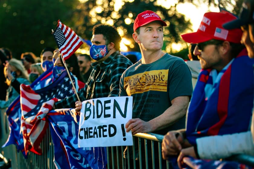 A Trump supporter with his clenched jaw holds a Biden Cheated sign at a Trump rally in Beverly Hills.