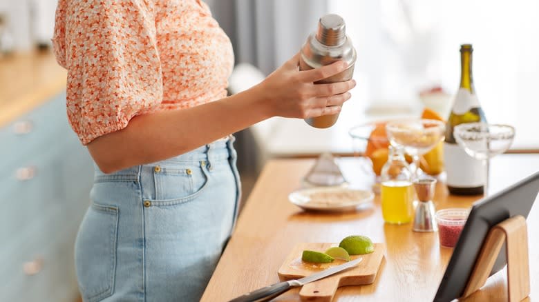 woman making cocktails, ingredients on counter