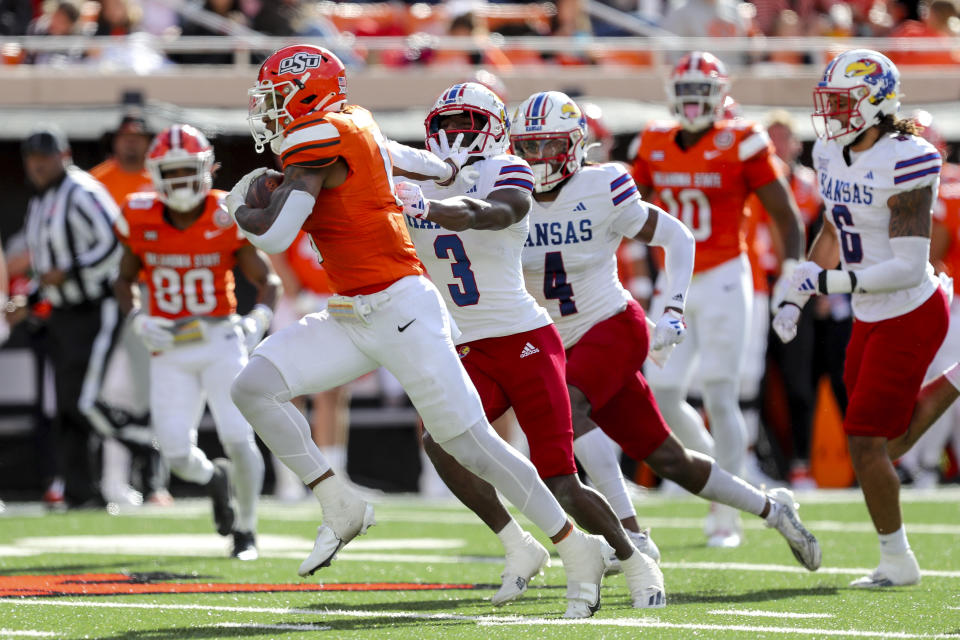 Oklahoma State's Ollie Gordon II (0) runs past Kansas's Mello Dotson (3) and Marvin Grant (4) for a touchdown during the second quarter of an NCAA college football game in Stillwater, Okla., Saturday, Oct. 14, 2023. (AP Photo/Mitch Alcala)