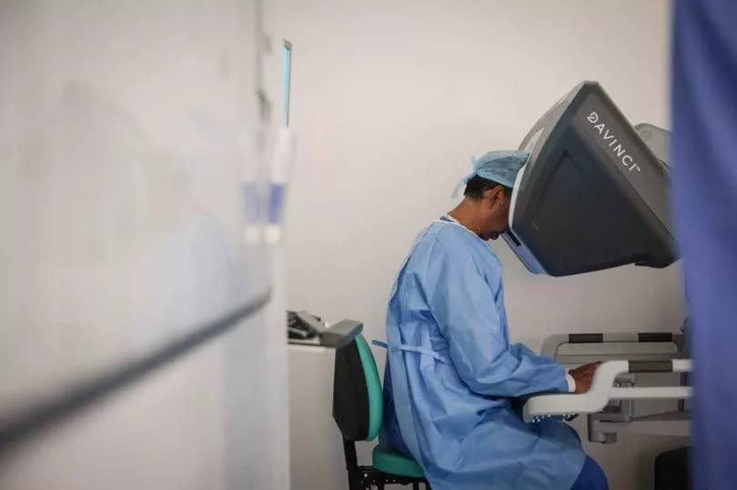 Mr Ramani operates the robot from a console -Credit:Kenny Brown | Manchester Evening News