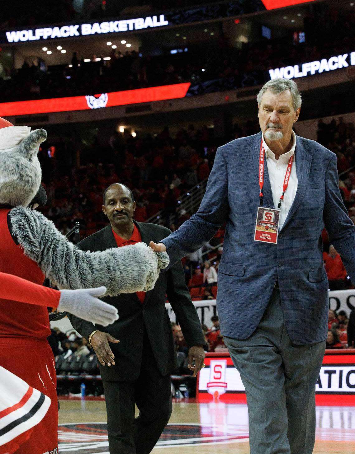 Tommy Burleson shakes hands with Mr. Wuf after members of the N.C. State men’s basketball 1974 national championship team were honored during a halftime ceremony on Saturday, Feb. 24, 2024, at PNC Arena in Raleigh, N.C.