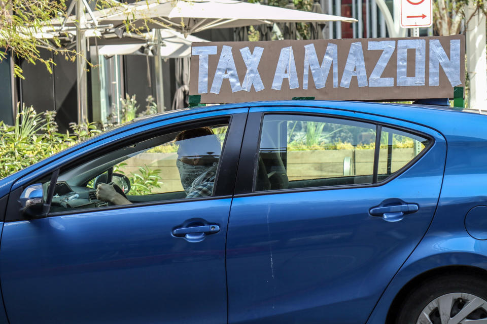 SEATTLE, UNITED STATES - MAY 01, 2020: A vehicle with a placard saying, 'tax Amazon' during the demonstration. A caravan of autos and bicyclists encircle Amazon headquarters demonstrating in support of city council member, Kshama Sawant's proposal to impose new taxes on Amazon and other large businesses, to fund COVID-19 relief and other programs.- PHOTOGRAPH BY Toby Scott / Echoes Wire/ Barcroft Studios / Future Publishing (Photo credit should read Toby Scott / Echoes Wire/Barcroft Media via Getty Images)