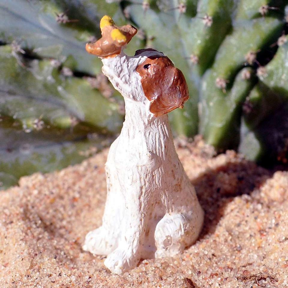 Miniature yellow and brown dog figure with a brown and yellow bird on its nose