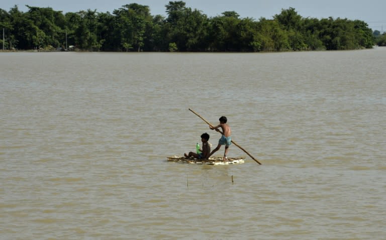 Indian children use a raft to travel over flood waters at Araria in Bihar