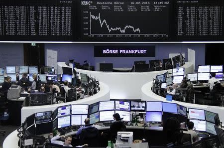 Traders work at their desks in front of the German share price index, DAX board, at the stock exchange in Frankfurt, Germany, February 16, 2016. REUTERS/Staff/remote