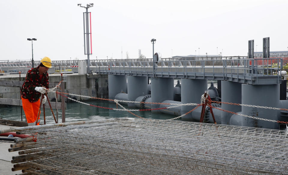 A worker stands on the construction site of the project in Venice, Italy, Friday, Nov. 29, 2019. The system of moveable under water barriers, dubbed Moses, has been beset by corruption, cost overruns and delays. Projected at 1.8 billion euros and to be completed by 2011, the project has cost 5.5 billion euros and won’t be operational before the end of 2021. (AP Photo/Antonio Calanni) A worker in Venice, Italy, Friday, Nov. 29, 2019. (AP Photo/Antonio Calanni)