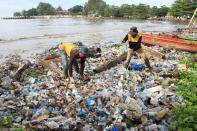 Workers clean up trash at a beach during World Environment Day