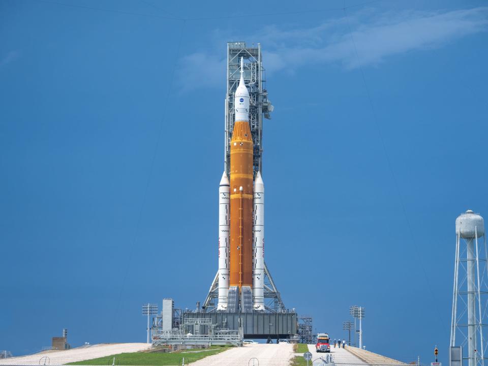 orange space launch system rocket stands upright against blue sky