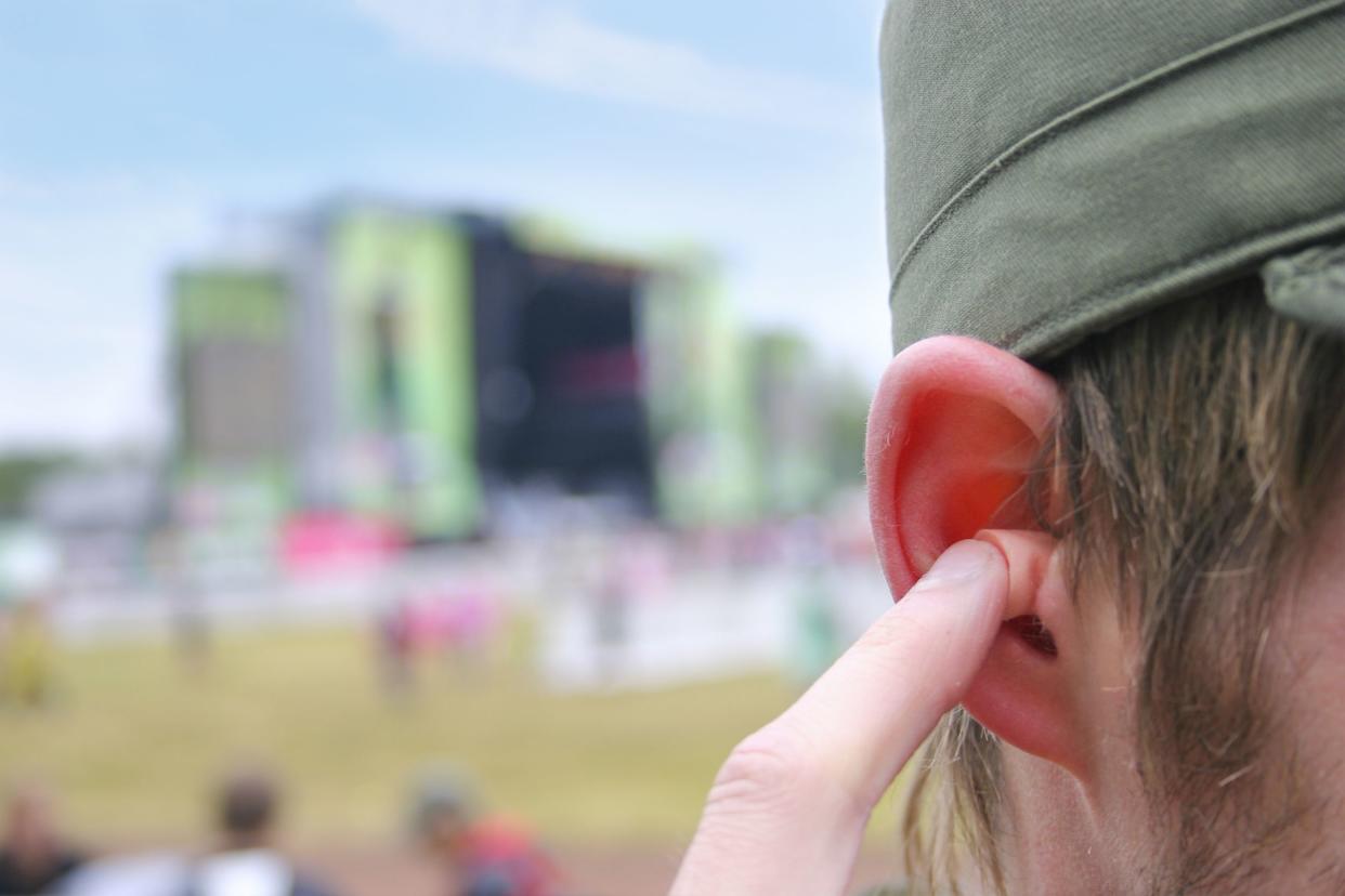 man putting in ear plugs while at music festival