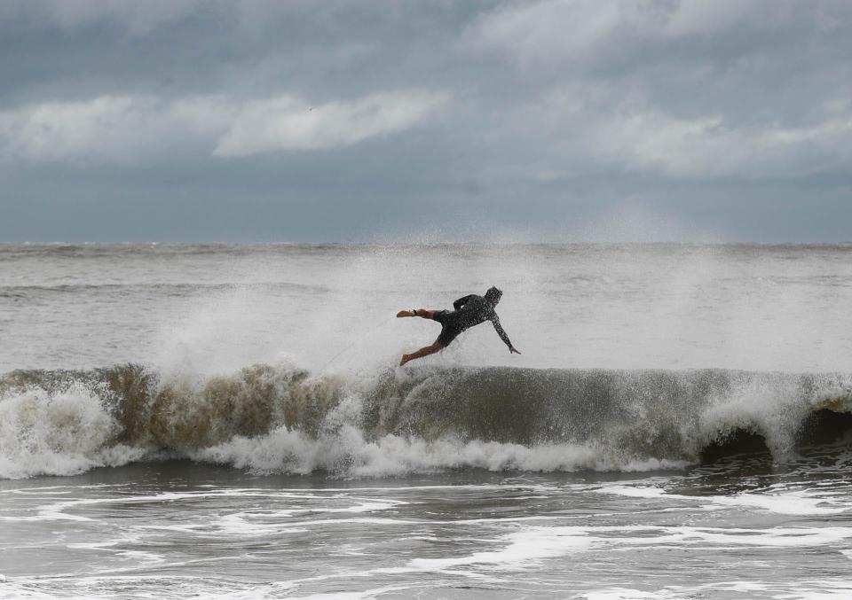 A surfer flies into the air as he rides the waves near the Tybee Island Pier as Hurricane Ian caused higher than normal surf as it passed the Georgia Coast on Friday September 30, 2022.