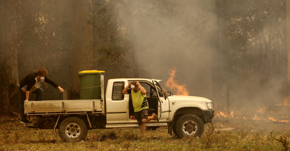 Jamie Fato prepares to stop an out of control fire entering Owen Whalan's property at Koorainghat, near Taree, New South Wales state, Tuesday, Nov. 12, 2019. Hundreds of schools remained closed across Australia's most populous state on Tuesday, Nov. 12, and residents were urged to evacuate woodlands for the relative safety of city centers as authorities braced for extreme fire danger. (Darren Pateman/AAP Images via AP)