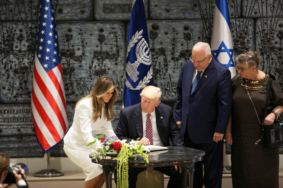 President Trump looks at his wife Melania signing a guest book