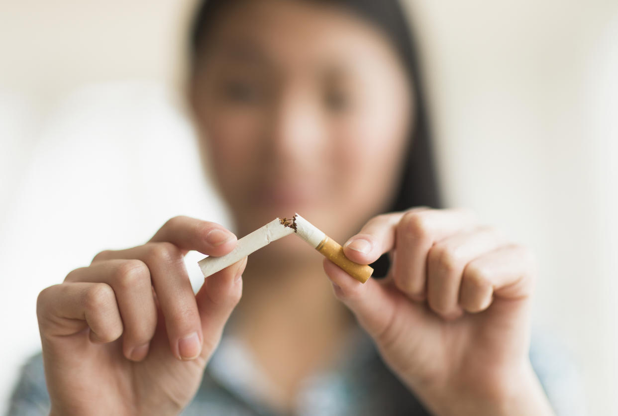 Mixed race teenage girl breaking cigarette in half