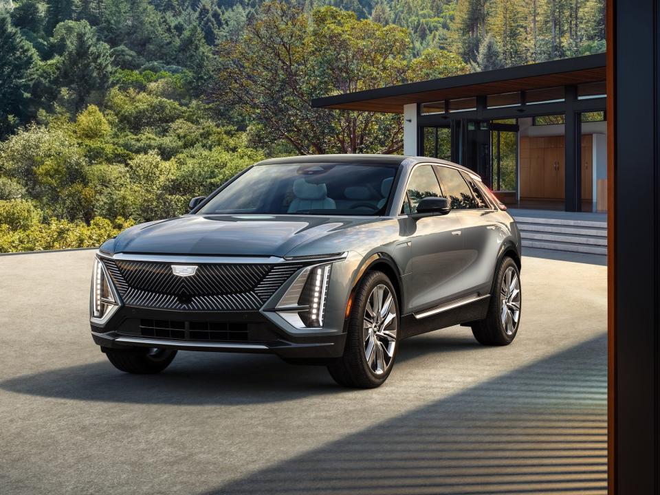 The 2023 Cadillac Lyriq parked in front of a home with trees in the background.