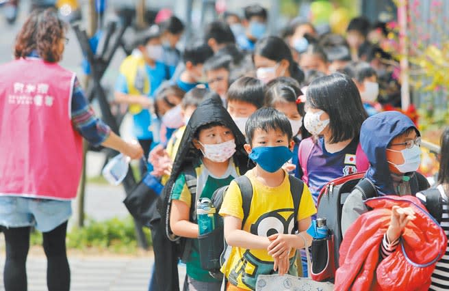 適逢開學季，有幼兒園、小學要求小朋友一整天戴口罩，引起家長不滿。圖為小朋友們個個戴口罩排隊進教室。（本報資料照片）