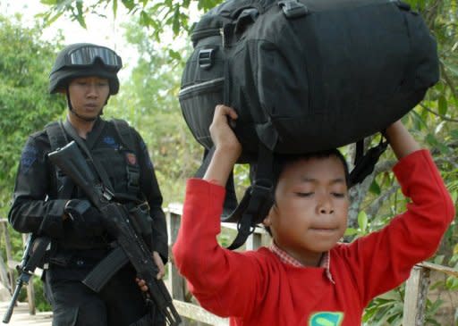 Indonesian police guard a Shiite Muslim boy as he is escorted to safety following attacks in Sampang on August 27. A mob attack on Shiites in Indonesia saw two men killed with sickles and dozens of homes torched, police and a human rights group said Monday, in the latest sign of rising intolerance in the world's largest Muslim country