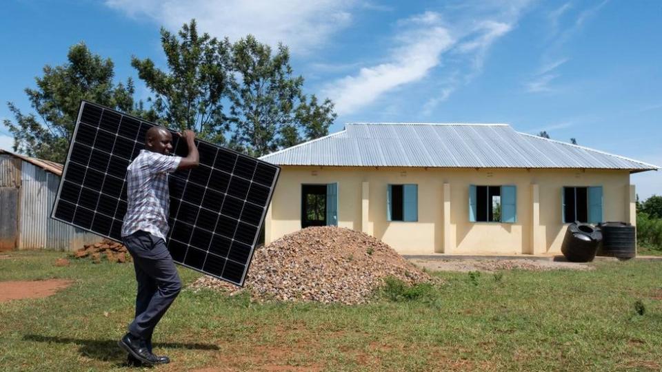 Hombre carga panel solar en Busia, Kenia.