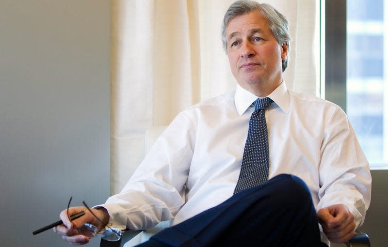 Jamie Dimon sits in his office holding his glasses and a pen in his right hand