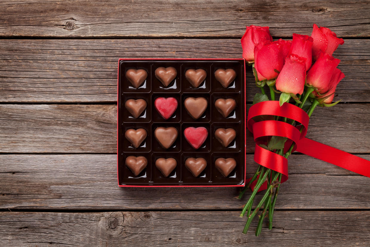 Valentines day with red roses and heart chocolate box on wooden table. Top view with space for your greetings