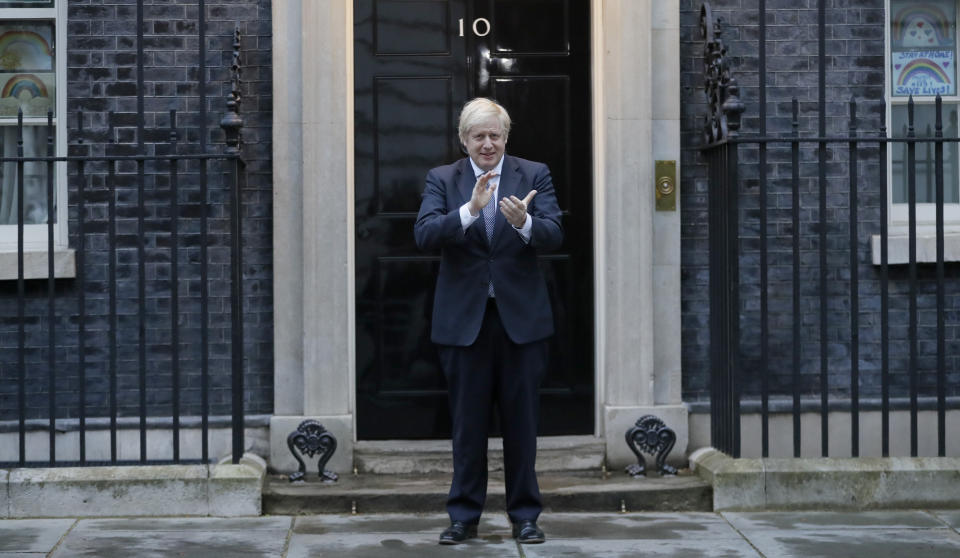 Britain's Prime Minister Boris Johnson applauds on the doorstep of 10 Downing Street in London during the weekly "Clap for our Carers" Thursday, April 30, 2020. The COVID-19 coronavirus pandemic has prompted a public display of appreciation for care workers. The applause takes place across Britain every Thursday at 8pm local time to show appreciation for healthcare workers, emergency services, armed services, delivery drivers, shop workers, teachers, waste collectors, manufacturers, postal workers, cleaners, vets, engineers and all those helping people with coronavirus and keeping the country functioning while most people stay at home in the lockdown. (AP Photo/Kirsty Wigglesworth)