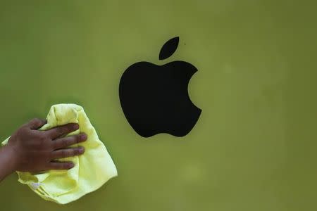 A worker wipes a poster advertisement for Apple's iPhone 5C on a wall of Japan's biggest mobile phone operator NTT Docomo Inc shop before its launch ceremony for the start of the selling of Apple's iPhone 5S and 5C at its shop in Tokyo, September 20, 2013. REUTERS/Yuya Shino/Files