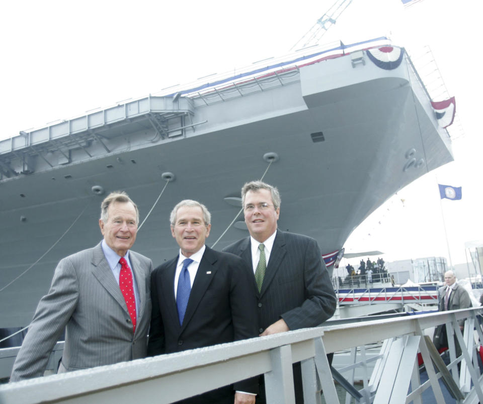 Former President George H.W. Bush, then-President George W. Bush and then-Florida Gov. Jeb Bush pose in front of the aircraft carrier George H.W. Bush after participating  in the christening ceremony in Newport News, Va., Saturday, Oct.. 7, 2006. (AP Photo/Lawrence Jackson)