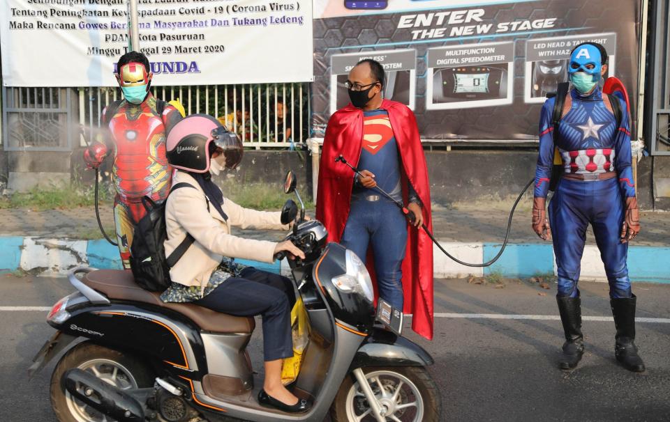 Police officers in superhero costumes spray disinfectant on motorists passing by during a coronavirus awareness campaign on a street in East Java, Indonesia, on April 9.