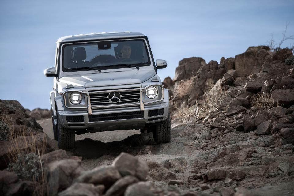 A gray Mercedes-Benz G550 driving on rocky terrain.