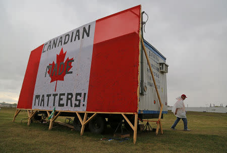 A striking member of the auto workers union Unifor walks to a picket line past a trailer covered by with a Canadian flag reading "Canadian Made Matters!", outside the General Motors Company (GM) CAMI assembly plant in Ingersoll, Ontario, Canada October 13, 2017. REUTERS/Chris Helgren