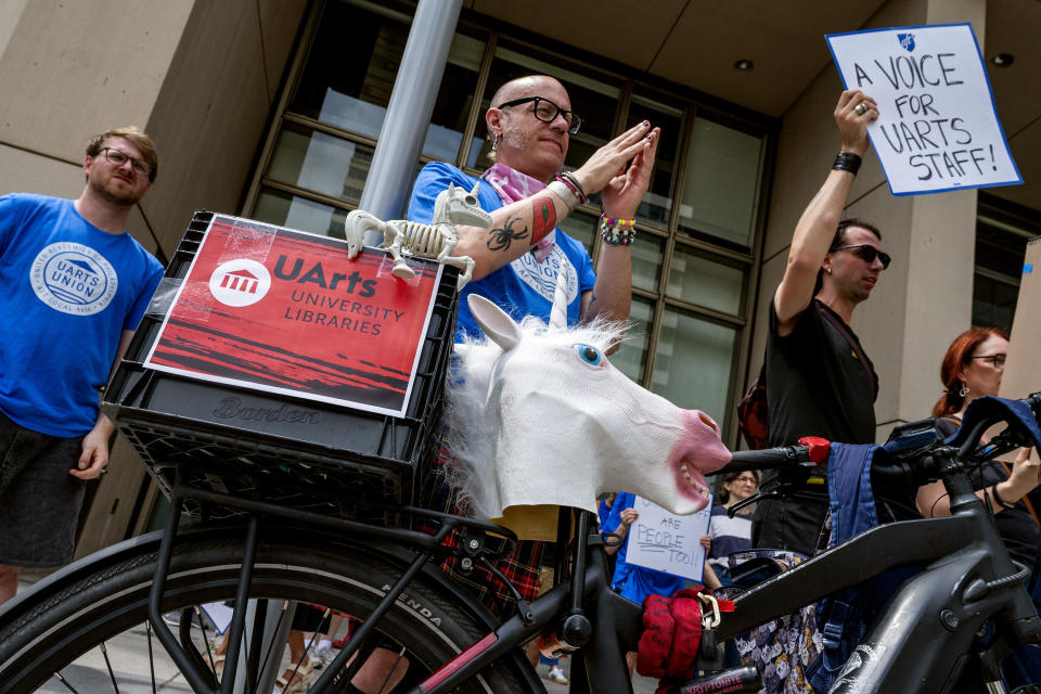 Justin Sewell, a librarian at the University of the Arts, joins a rally with a unicorn - the school mascot - as students, staff, and faculty rally outside 1500 Market Wednesday June 5, 2024 in front of the former law offices of UArts chair Jud Aaron. Their march stated at Hamilton Hall on their campus. (Tom Gralish/The Philadelphia Inquirer via AP)