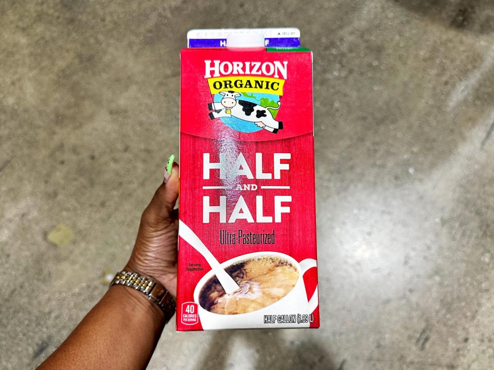 The writer holds a red carton with white letters spelling out "half and half" with an image of a coffee cup and half and half pouring into it