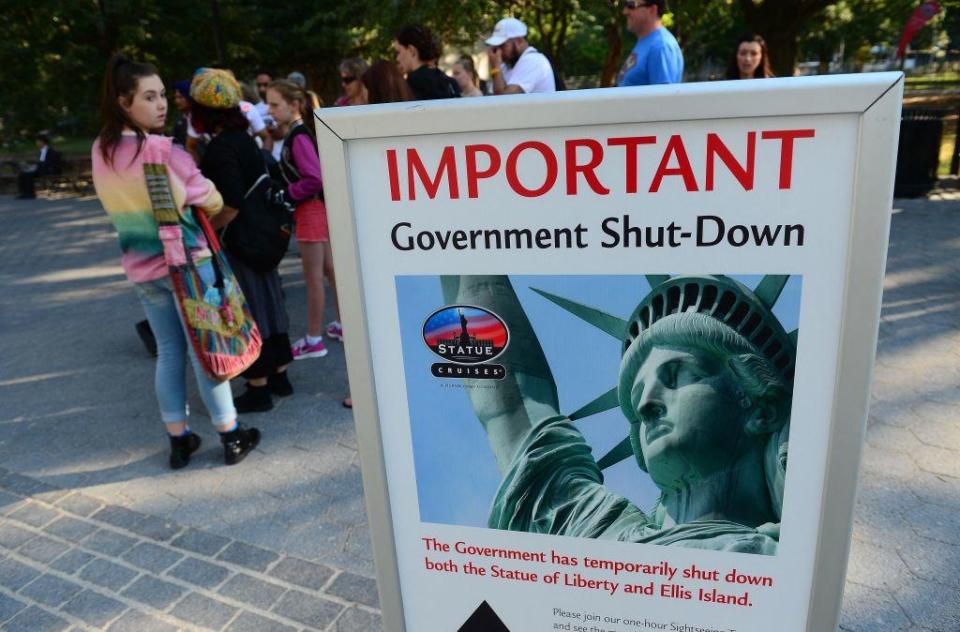 Tourists walk by a sign announcing that the Statue of Liberty is closed due to a government shutdown in New York on Oct. 1, 2013. / Credit: AFP PHOTO/Emmanuel Dunand