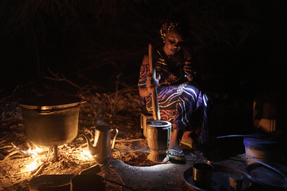 Houraye Ndiaye, 20, daughter of Amadou Altine Ndiaye, prepares dinner for her family after setting up camp in the village of Yawara Dieri, in the Matam region of Senegal, Saturday, April 15, 2023. Meals for Ndiaye’s family rarely include meat and are carefully planned. Only when they pass through certain villages can they stock up on food — vegetables, rice and other essentials. (AP Photo/Leo Correa)