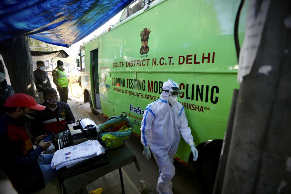 A health worker walks past a mobile testing van meant for taking samples to test for COVID-19 in New Delhi, India, Saturday, Dec. 19, 2020. India’s confirmed coronavirus cases have crossed 10 million with new infections dipping to their lowest levels in three months, as the country prepares for a massive COVID-19 vaccination in the new year. (AP Photo/Manish Swarup)