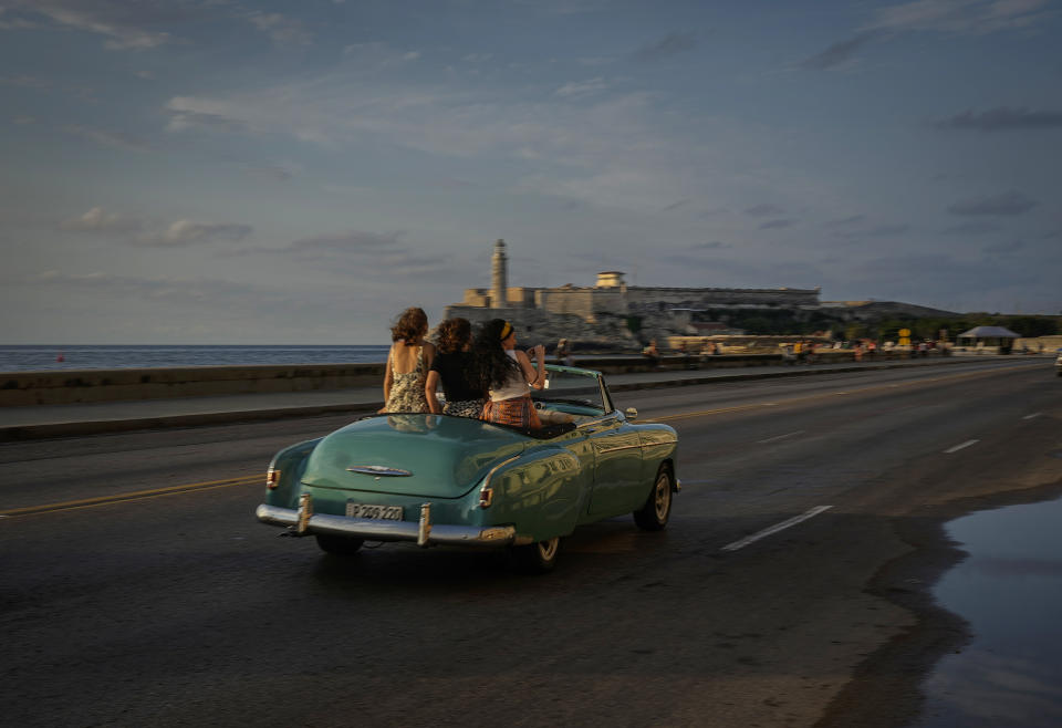 Turistas dan un paseo por el Malecón en un automóvil estadounidense antiguo en La Habana, Cuba, el lunes 16 de mayo de 2022. El gobierno de Joe Biden anunció que ampliará los vuelos a Cuba y levantará las restricciones de la era de Donald Trump sobre las remesas que los inmigrantes pueden enviar a la isla. (AP Foto/Ramón Espinosa)