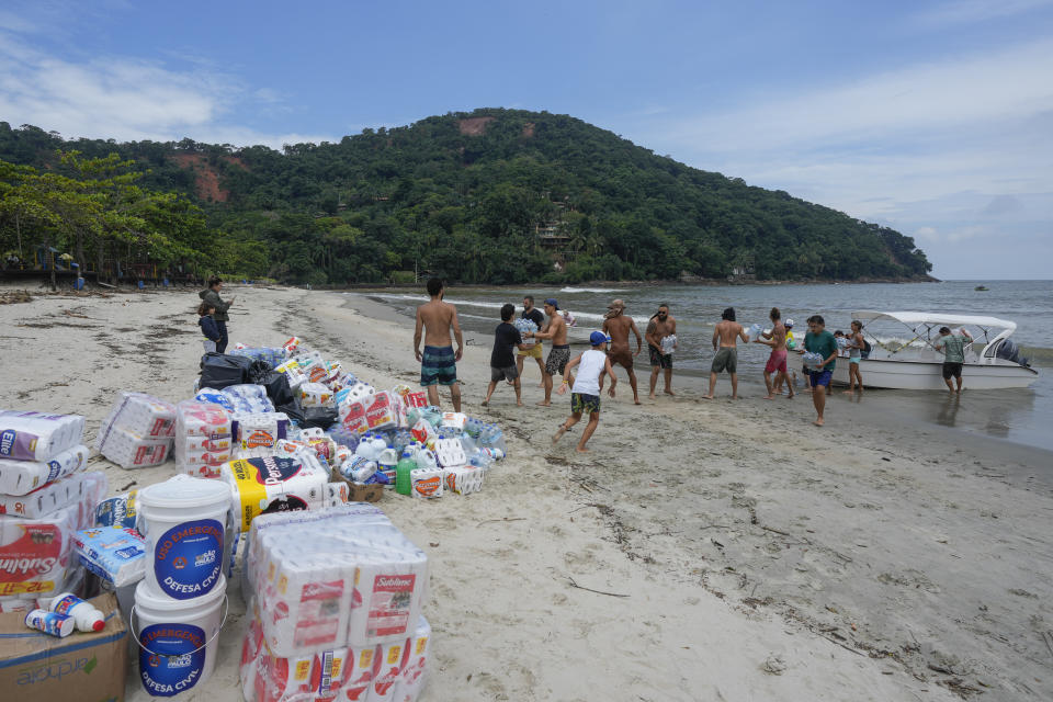 Volunteers unload donations on Barra do Sahi beach after deadly landslides triggered by heavy rain in the coastal city of Sao Sebastiao, Brazil, Wednesday, Feb. 22, 2023. (AP Photo/Andre Penner)