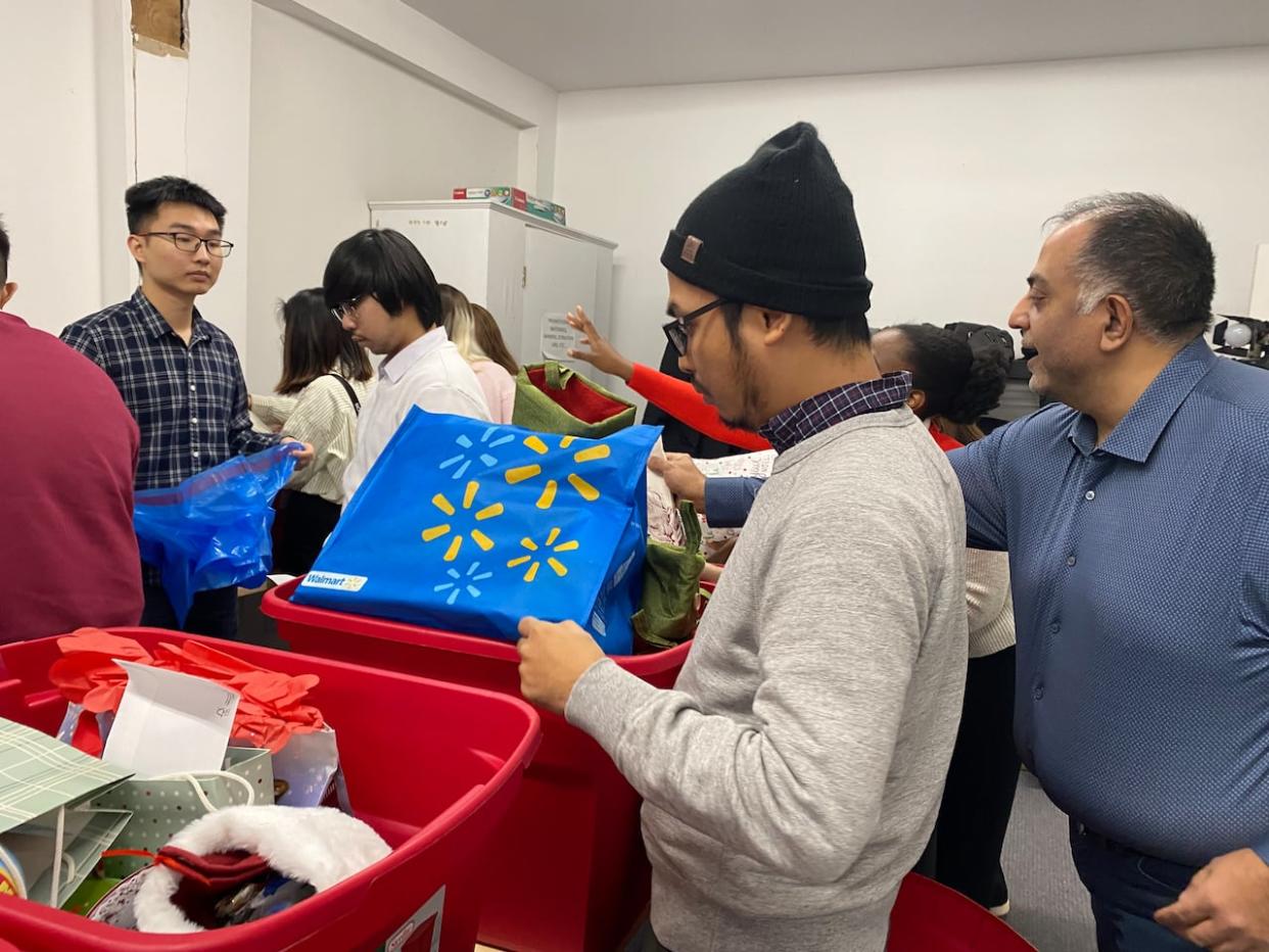 Volunteers sort dozens of donated presents at Parker Street Food and Furniture Bank that will be handed out next week to families who have registered for help.  (Carolyn Ray/CBC - image credit)