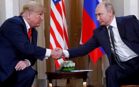 US President Donald Trump, left, and Russian President Vladimir Putin, right, shake hands at the beginning of a meeting at the Presidential Palace in Helsinki, Finland - Credit: Pablo Martinez Monsivais/AP