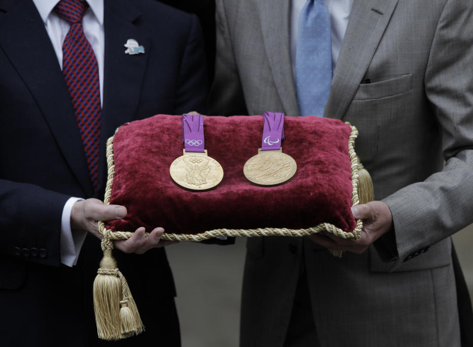 Sebastian Coe, right, chairman of the London 2012 Organizing Committee, and Jan du Plessis, left, Rio Tinto mining company chairman, pose for the photographers holding a gold medal of the Games, during a photo op at the Tower of London, in London, Monday, July 2, 2012 The company is responsible for the production of the precious metals for the London 2012 Games medals, and has handed over the final Olympic and Paralympic medals to LOCOG for secure storage in the vaults at the Tower of London during the Games. The gold, silver and bronze medals which will be awarded to the athletes at Games-times, will remain there until they are needed for the Victory Ceremonies. In total, 4,700 medals have been produced and will be awarded in 805 Victory Ceremonies that will take place in over 30 London 2012 venues across the UK. (AP Photo/Lefteris Pitarakis)