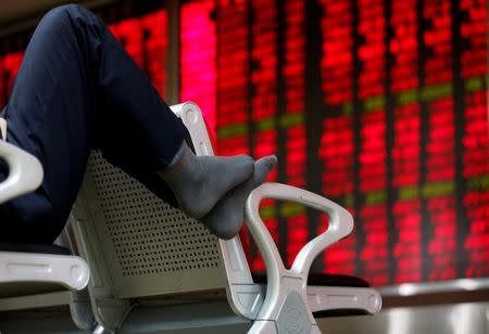 An investor puts his feet on a chair in front of an electronic board showing stock information at a brokerage house in Beijing, China, February 16, 2016.REUTERS/Kim Kyung-Hoon/File Photo