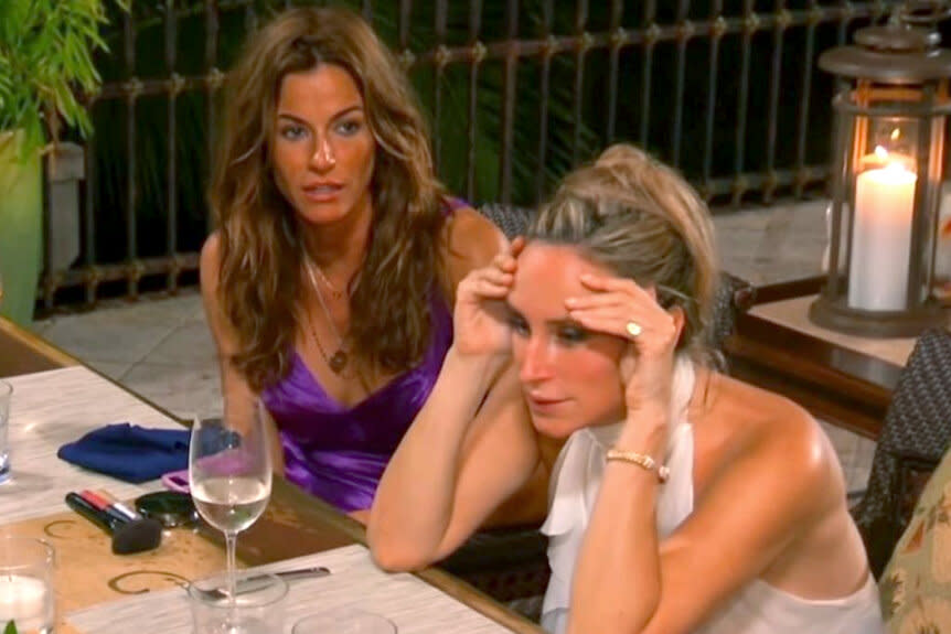 Kelly Bensimon and Sonja Morgan sitting at a table having a conversation while on vacation.