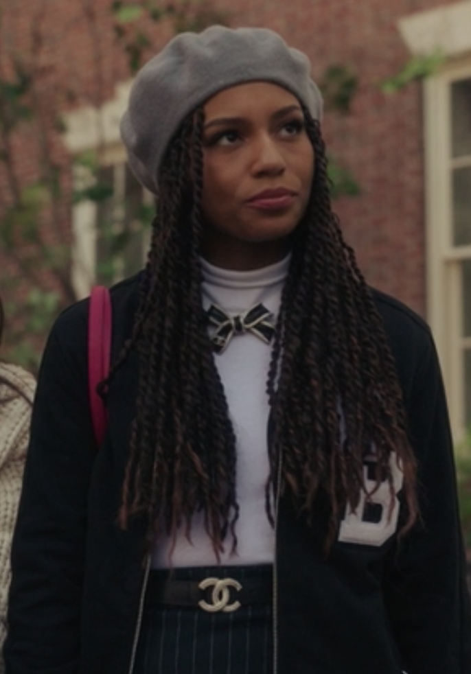 Monet wears a high waisted pin stripe skirt with a t-shirt tucked into it under a dark letterman jacket and a beret