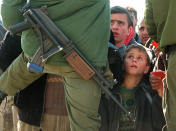 <p>A Palestinian boy clings to the hand of his father, who is holding his identity card, and looks up at an Israeli soldier armed with a Galil assault rifle at the Bethlehem checkpoint in southern Jerusalem, Jan. 9, 1998. (Photo: Jacqueline Larma/AP) </p>