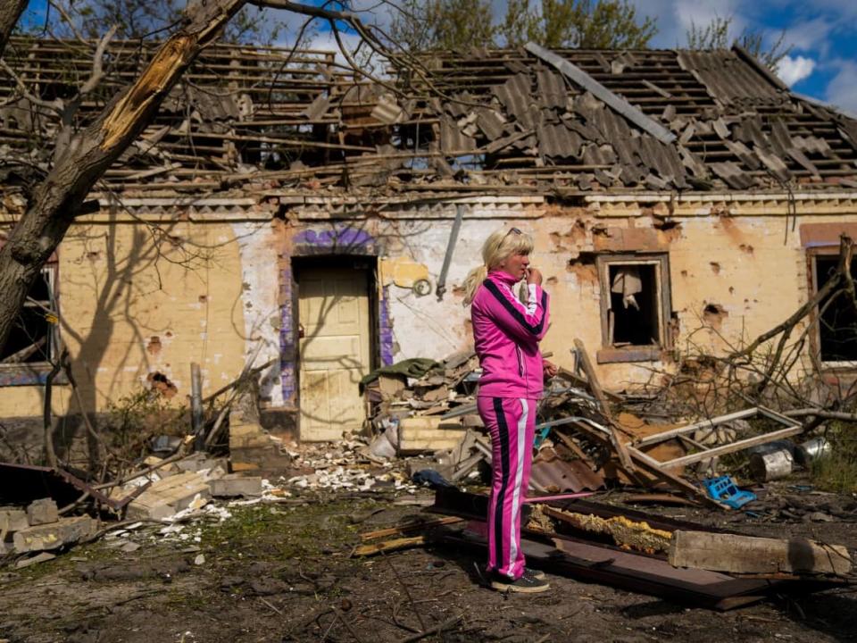 Iryna Martsyniuk, 50, stands next to her house, heavily damaged by Russian bombing, in Velyka Kostromka village, Ukraine on May 19, 2022. (Associated Press/Francisco Seco - image credit)