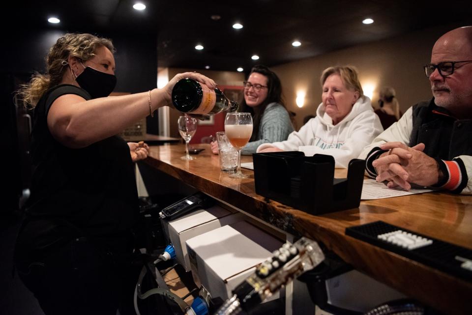 Stacey Miscisim, left, a server at Embers Smokehouse and Tap, fills a glass for customers, Miriam Blumenfeld, center left, of Chalfont; Lori Franklin, center right, of New Britain Borough; and Cliff Franklin, of New Britain Borough; on Thursday, January 13, 2022. Under the ownership of Chef Scott Borghi and Alisha Riexinger, the new restaurant opened last month in Chalfont.