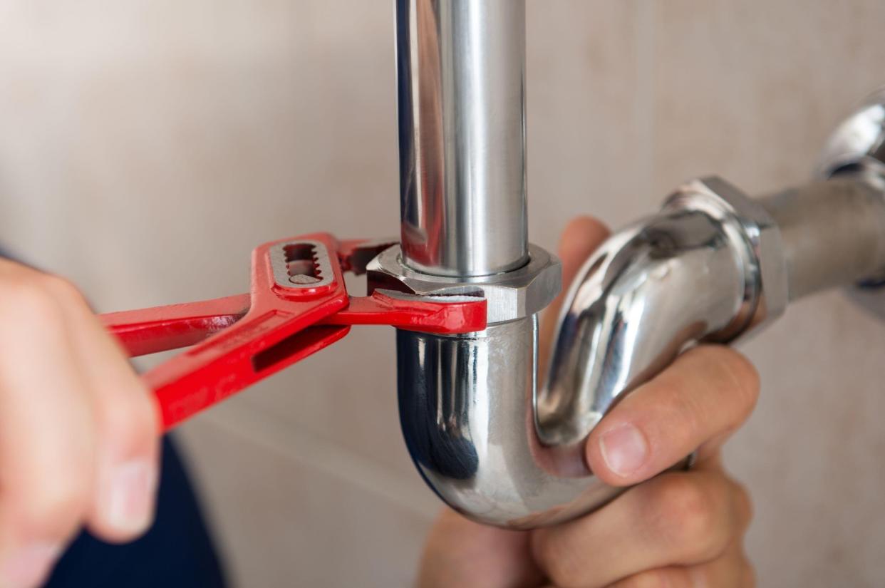 closeup of plumber fixing pipe with wrench