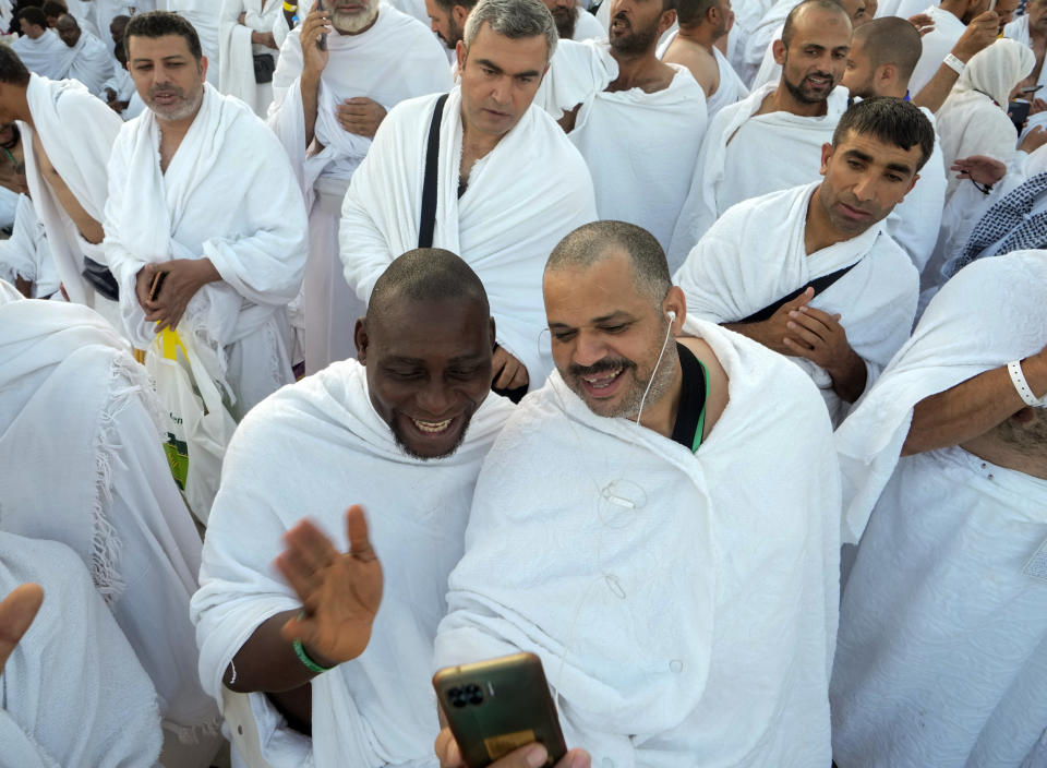 Muslim pilgrims make a video call to their relative on the rocky hill known as the Mountain of Mercy, on the Plain of Arafat, during the annual hajj pilgrimage, near the holy city of Mecca, Saudi Arabia, Friday, July 8, 2022. One million pilgrims from across the globe amassed on Thursday in the holy city of Mecca in Saudi Arabia to perform the initial rites of the hajj, marking the largest Islamic pilgrimage since the coronavirus pandemic upended the annual event, a key pillar of Islam. (AP Photo/Amr Nabil)