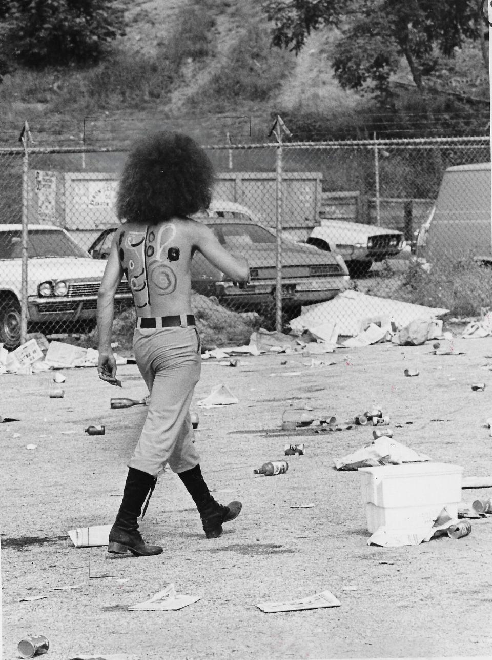 A rock fan strolls across a litter-strewn lot at the Rubber Bowl in 1972.