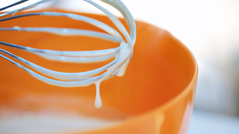 Pancake batter dripping off a whisk