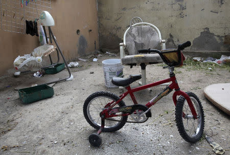 An abandoned bicycle for children, a baby swing and rubbish are seen in the back patio of a house seized by authorities in Ciudad Juarez May 23, 2014. REUTERS/Jose Luis Gonzalez